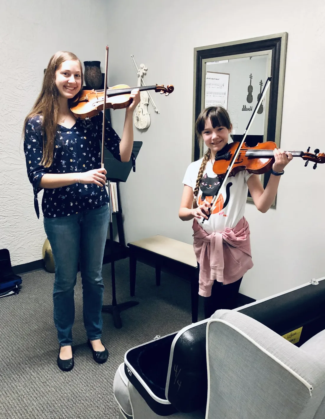 Two students playing violin together during a lesson.