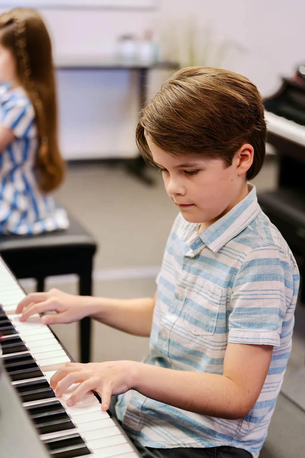 A young student concentrating at the piano during a summer session.
