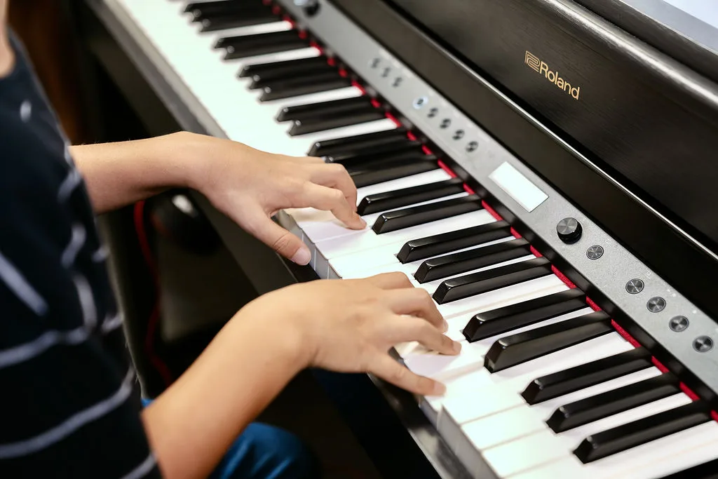 Young hands on a keyboard during a group music class.