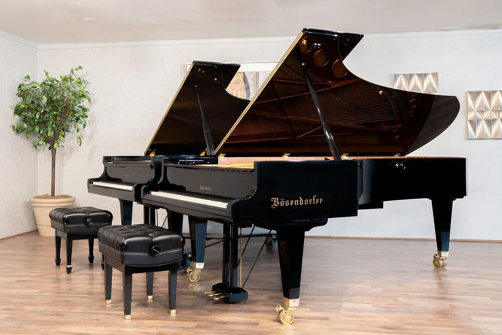 Dual grand pianos under stage light in the Liszt Recital Hall.