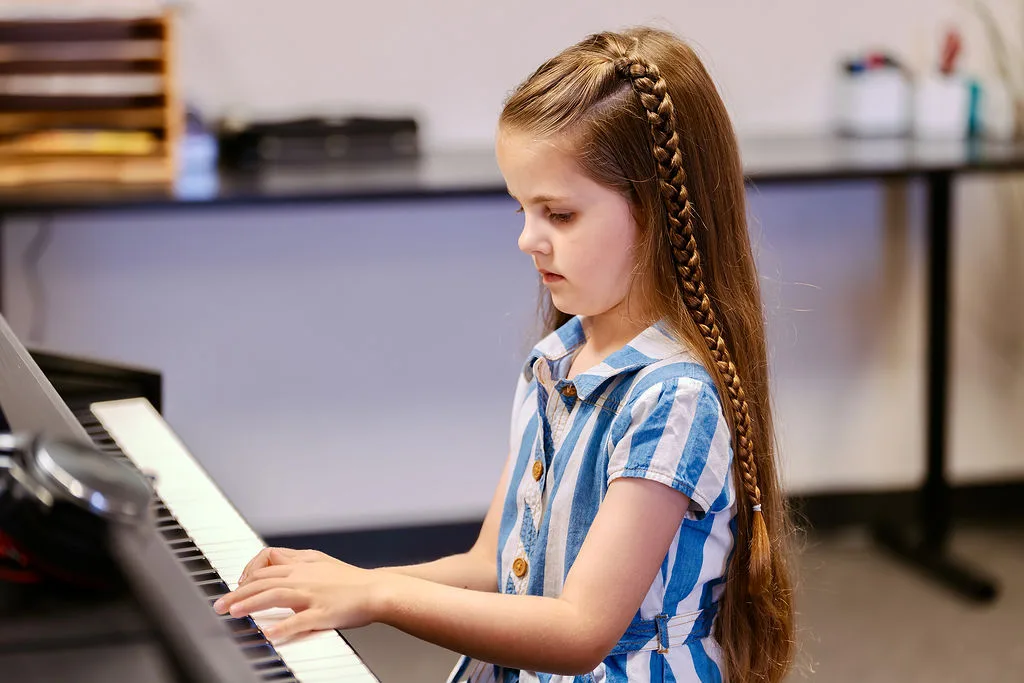 A student playing piano in close profile during a lesson.