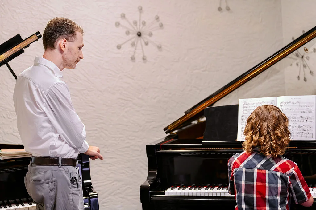 An instructor and student reading through sheet music together.