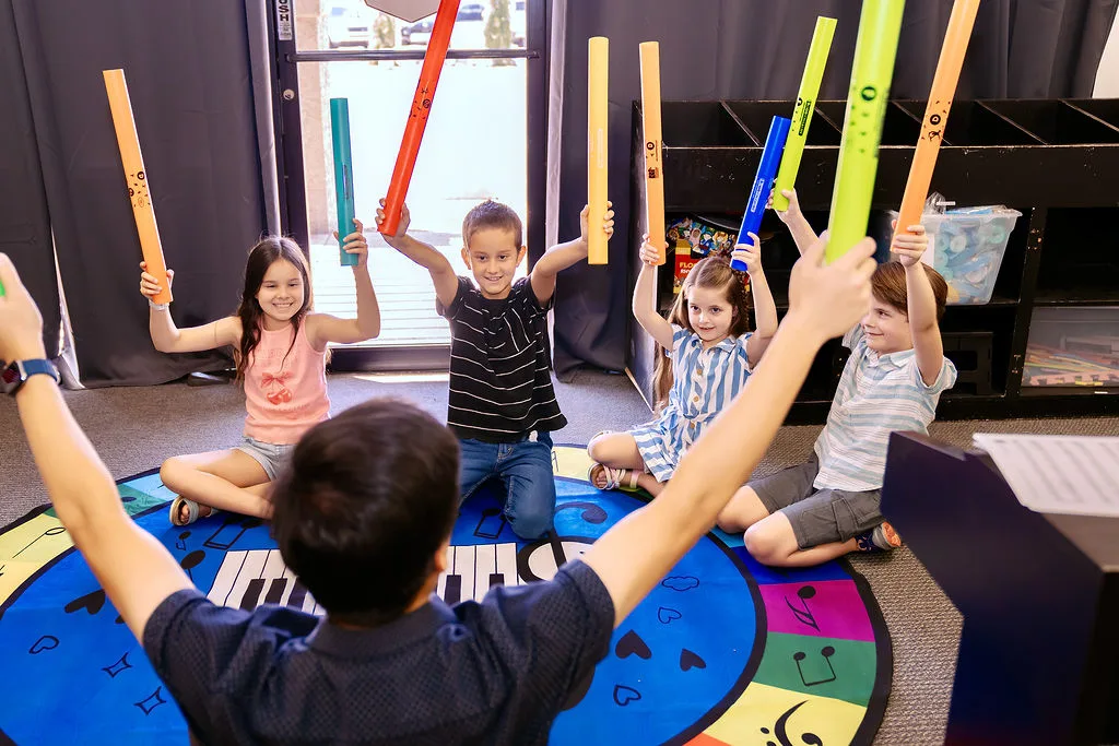 Young campers playing rhythm sticks during summer camp.