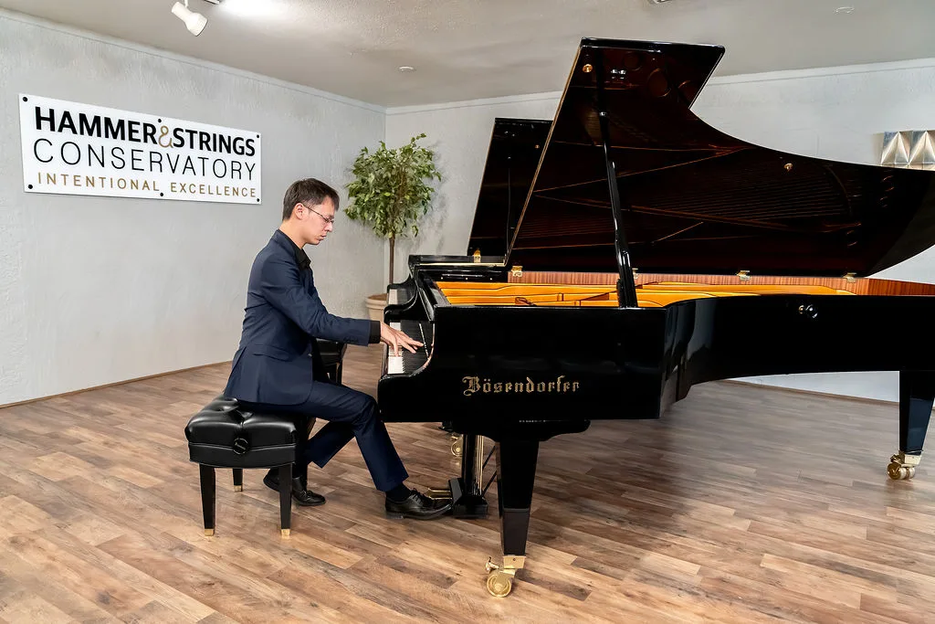 A student performing beneath the Hammer and Strings Conservatory sign.