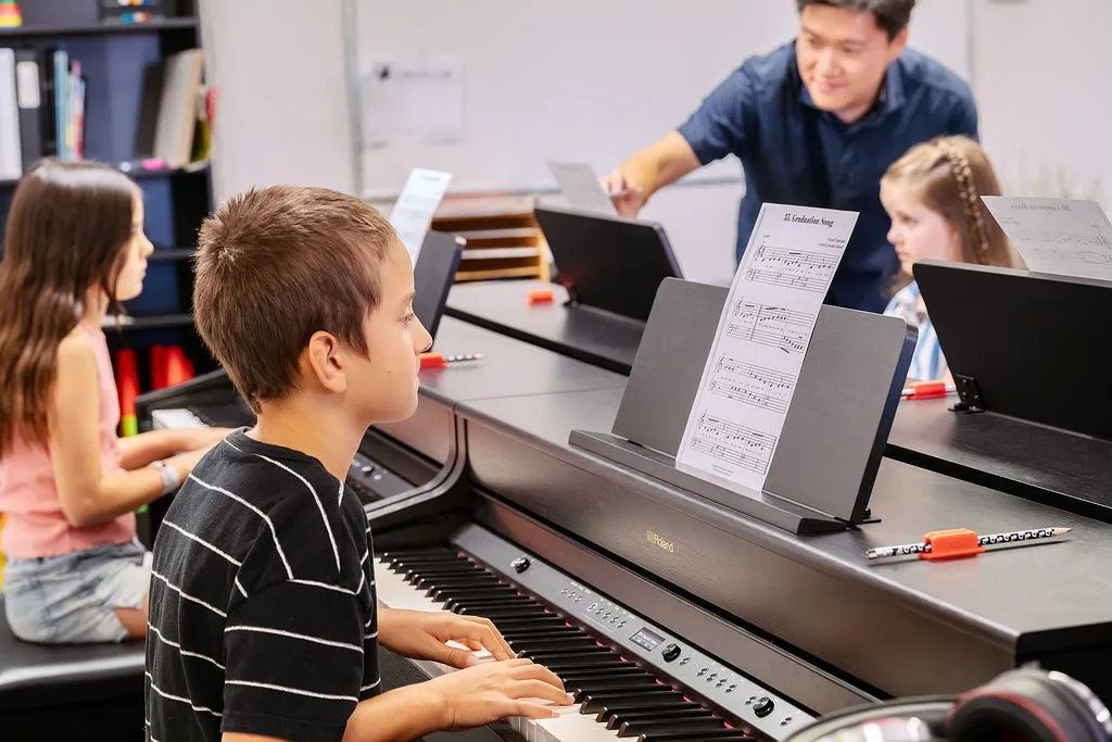 Students at a row of digital pianos during a group piano class.