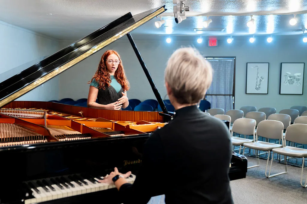 A student performing on the Conservatory recital hall stage.