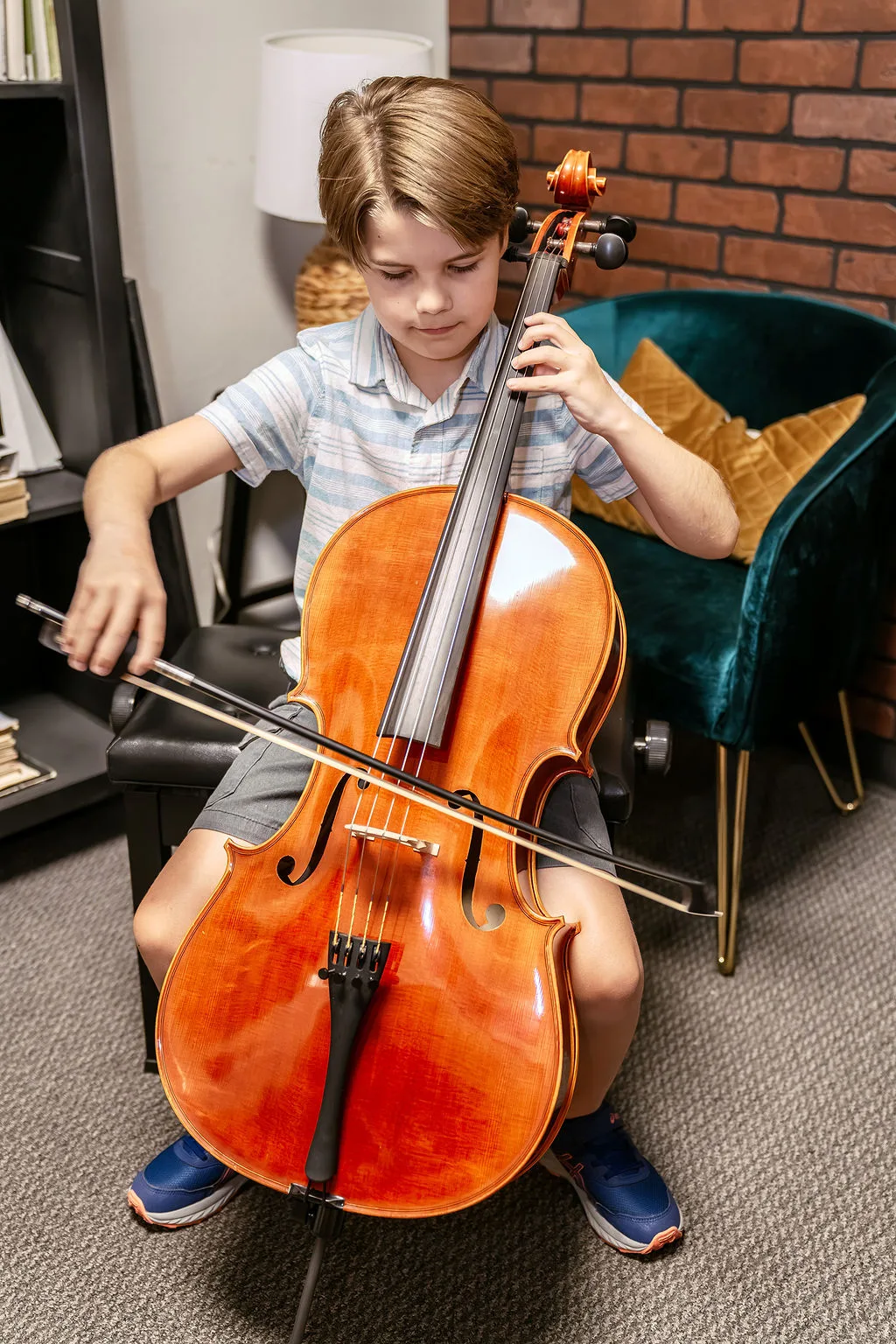 A student playing cello in a practice room.