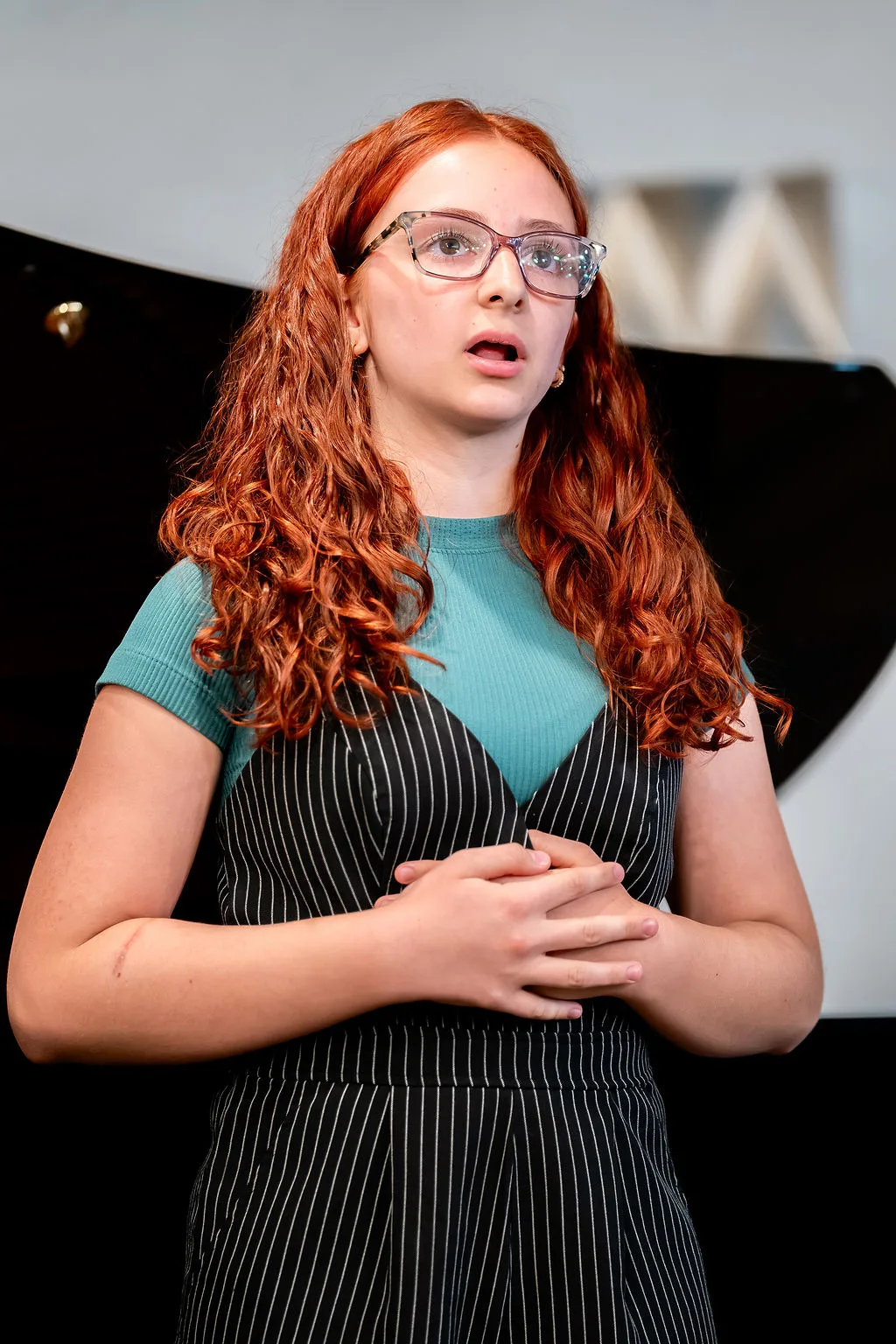 A young vocalist singing during a performance.
